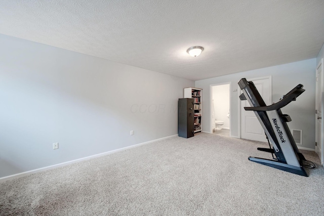 workout room with light colored carpet and a textured ceiling