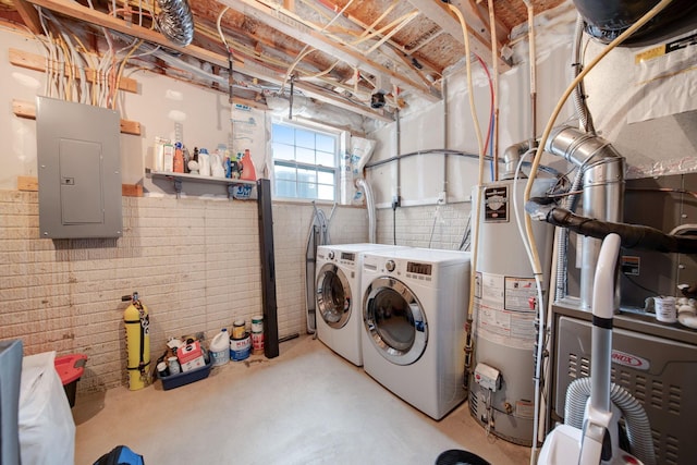 laundry room featuring brick wall, independent washer and dryer, electric panel, and water heater