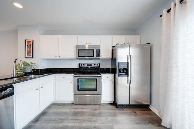 kitchen with sink, white cabinets, light wood-type flooring, and appliances with stainless steel finishes