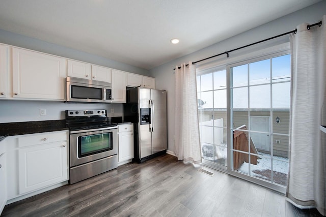 kitchen with white cabinets, dark hardwood / wood-style flooring, and appliances with stainless steel finishes