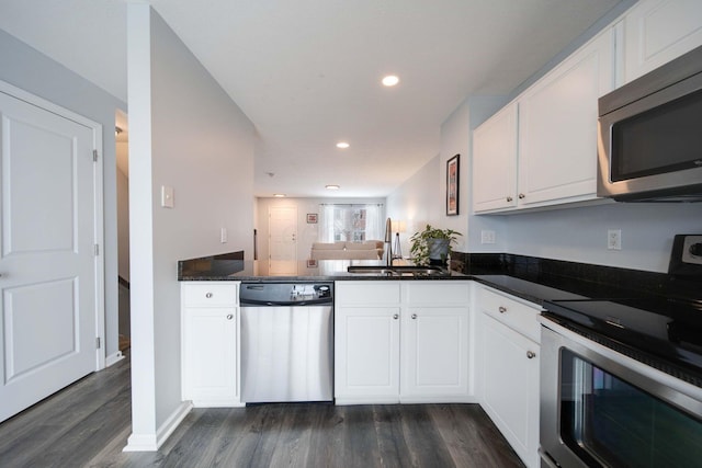 kitchen with appliances with stainless steel finishes, dark hardwood / wood-style floors, white cabinetry, and sink