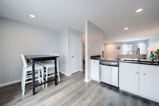 kitchen with white cabinetry, sink, stainless steel dishwasher, and light hardwood / wood-style floors