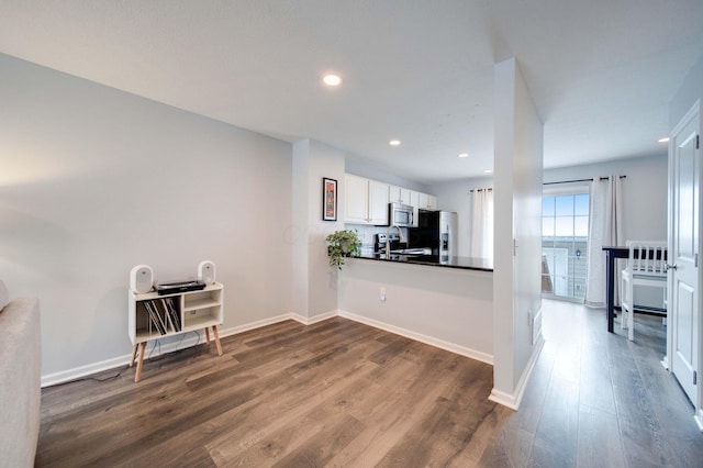 kitchen with kitchen peninsula, white cabinetry, hardwood / wood-style floors, and appliances with stainless steel finishes