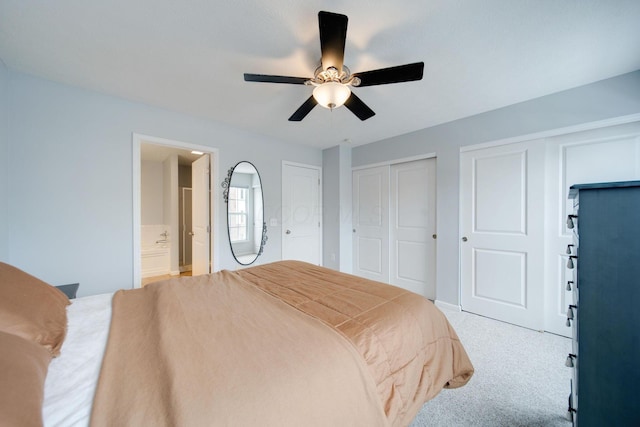 carpeted bedroom with ensuite bath, ceiling fan, and multiple closets