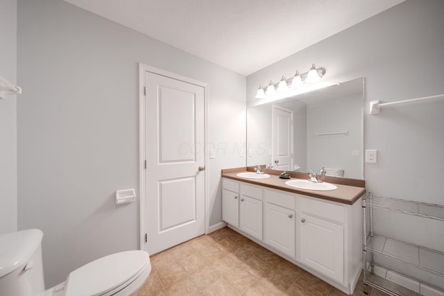 bathroom featuring a textured ceiling, vanity, and toilet