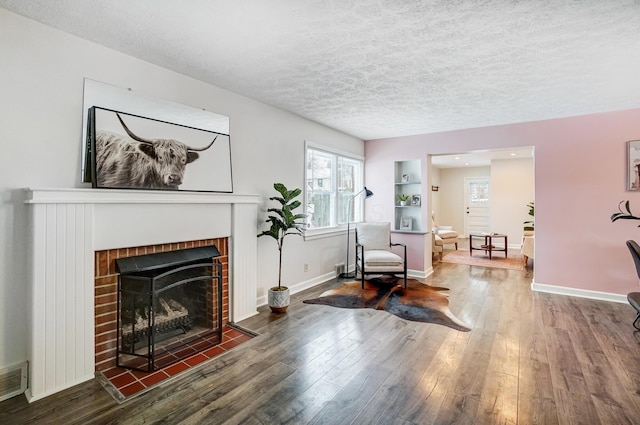 sitting room with dark wood-type flooring, a fireplace, and a textured ceiling