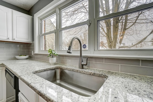 details with sink, dishwasher, light stone countertops, white cabinets, and decorative backsplash