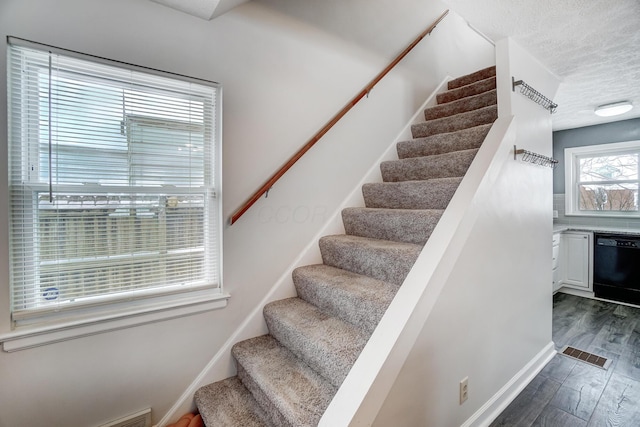 stairway with hardwood / wood-style flooring and a textured ceiling