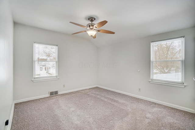 carpeted empty room featuring lofted ceiling, plenty of natural light, and ceiling fan