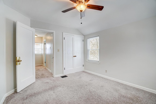 unfurnished bedroom with light carpet, lofted ceiling, a closet, and ceiling fan