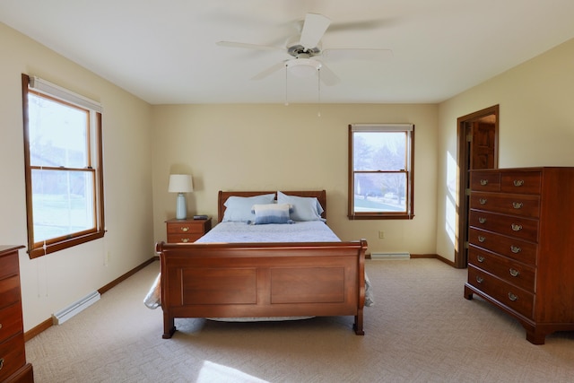 bedroom with ceiling fan, light colored carpet, baseboard heating, and multiple windows