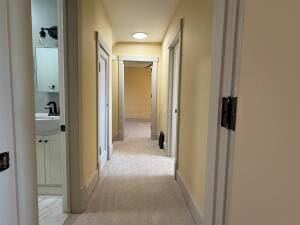 hall featuring light colored carpet and sink