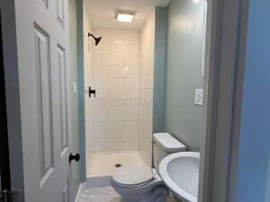 bathroom featuring sink, toilet, and tiled shower