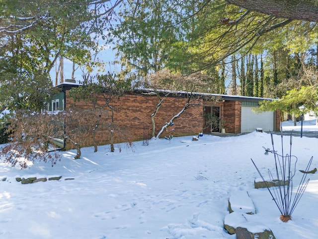 view of snowy exterior featuring a garage