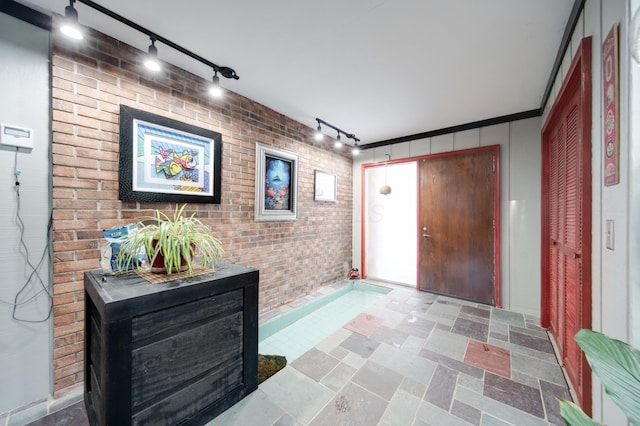 foyer featuring brick wall and crown molding