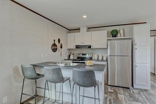 kitchen featuring sink, kitchen peninsula, a breakfast bar area, white cabinets, and appliances with stainless steel finishes