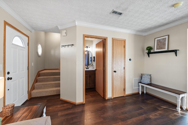 foyer with dark hardwood / wood-style flooring, a textured ceiling, and ornamental molding