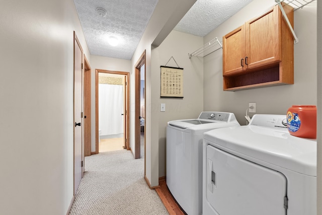 laundry room featuring cabinets, independent washer and dryer, and a textured ceiling