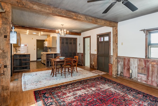 dining area featuring beam ceiling, wood-type flooring, and ceiling fan with notable chandelier