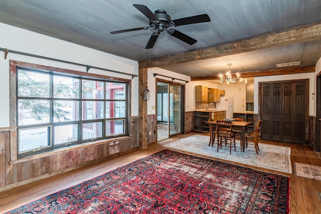 dining space featuring wood-type flooring, wooden walls, and plenty of natural light