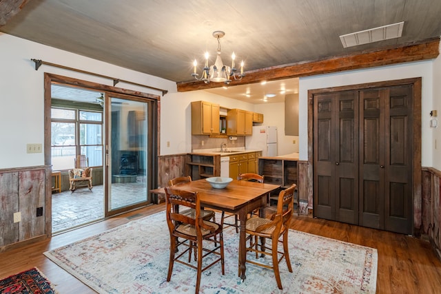 dining area featuring an inviting chandelier, wooden walls, dark hardwood / wood-style flooring, and sink