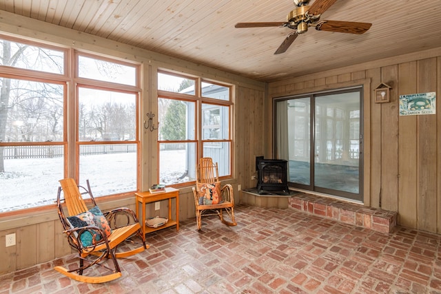 sunroom featuring wooden ceiling, ceiling fan, and a wood stove