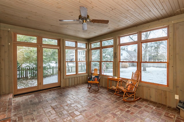 unfurnished sunroom with ceiling fan, a wealth of natural light, and wood ceiling