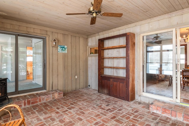 interior space featuring ceiling fan, a wood stove, and wood ceiling