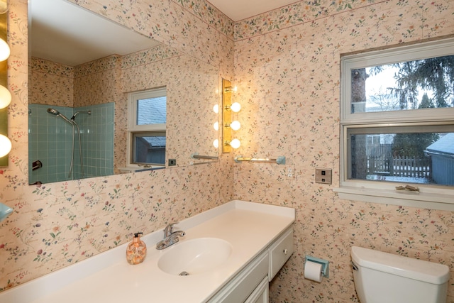 bathroom with vanity, toilet, and tiled shower