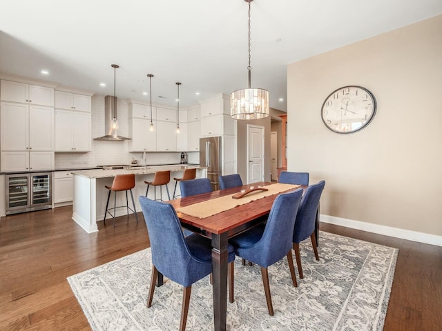 dining room with dark wood-type flooring, beverage cooler, and an inviting chandelier