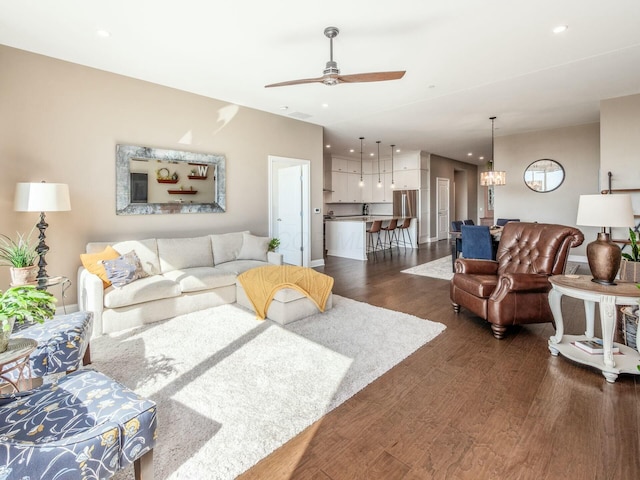 living room with dark wood-type flooring and ceiling fan with notable chandelier