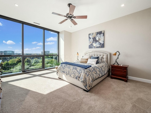 bedroom with ceiling fan, expansive windows, and carpet flooring