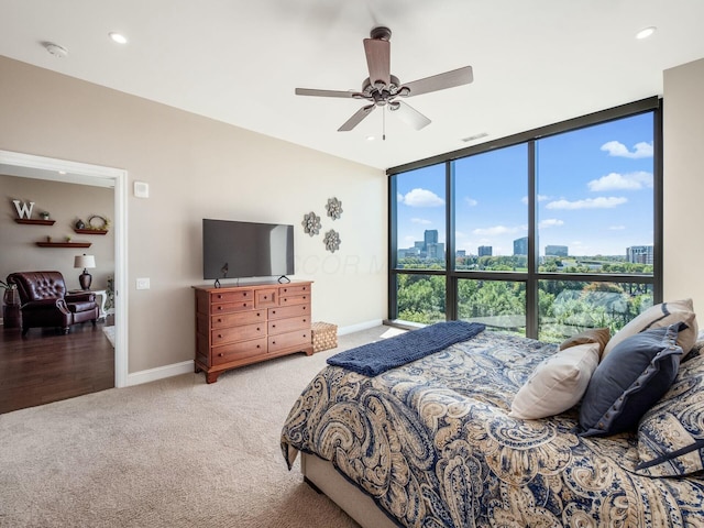 bedroom featuring ceiling fan, a wall of windows, and carpet floors