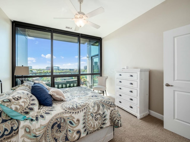 carpeted bedroom featuring ceiling fan, multiple windows, and floor to ceiling windows