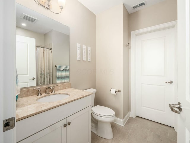 bathroom with toilet, vanity, and tile patterned flooring