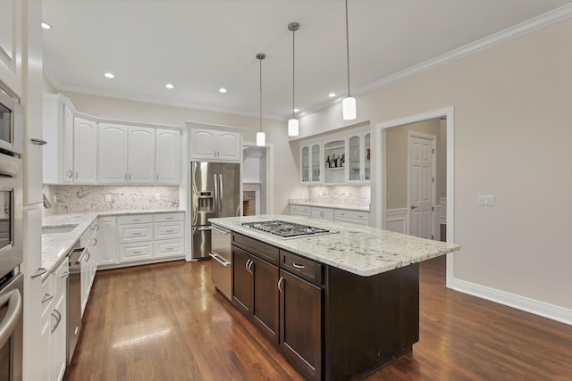 kitchen with light stone countertops, tasteful backsplash, stainless steel appliances, white cabinetry, and hanging light fixtures