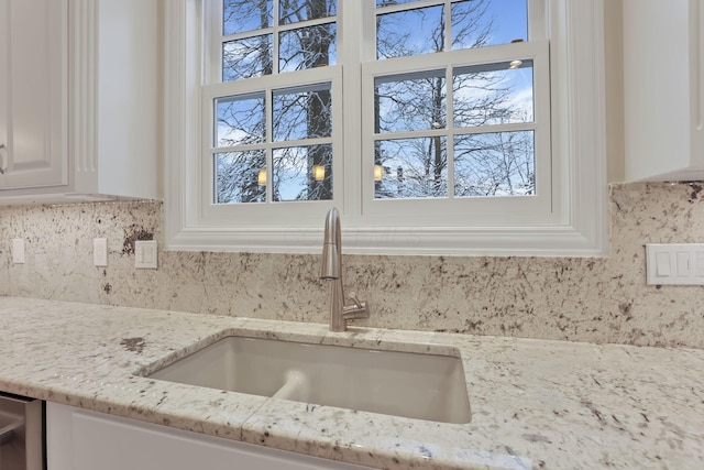 room details with light stone countertops, white cabinets, and sink