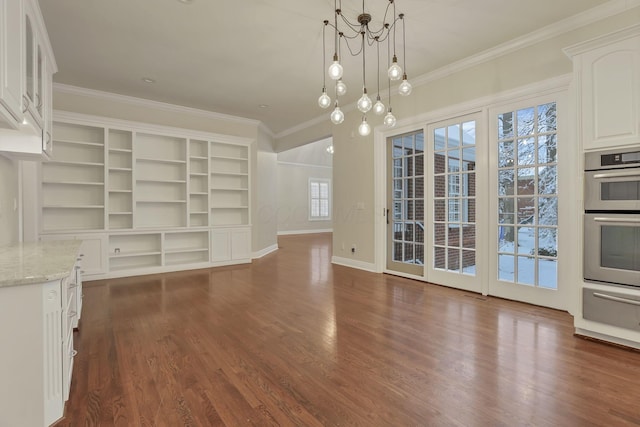 unfurnished living room with dark hardwood / wood-style flooring, an inviting chandelier, a wealth of natural light, and ornamental molding