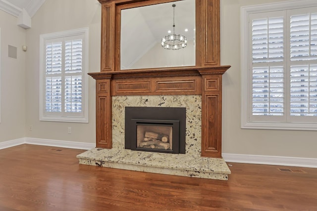 room details featuring hardwood / wood-style floors, an inviting chandelier, crown molding, and a premium fireplace