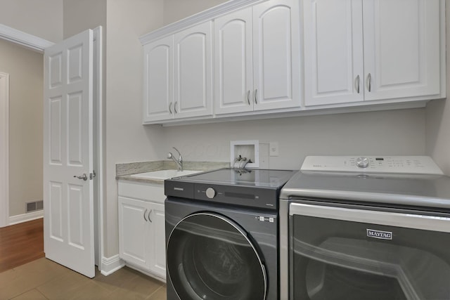 clothes washing area featuring cabinets, dark wood-type flooring, sink, and washing machine and clothes dryer