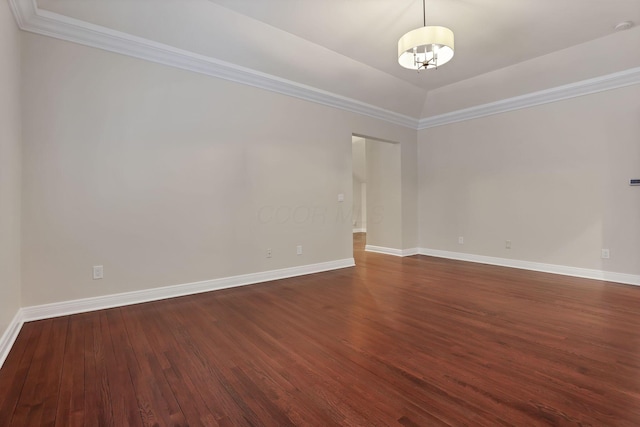 empty room featuring dark hardwood / wood-style flooring, vaulted ceiling, and ornamental molding