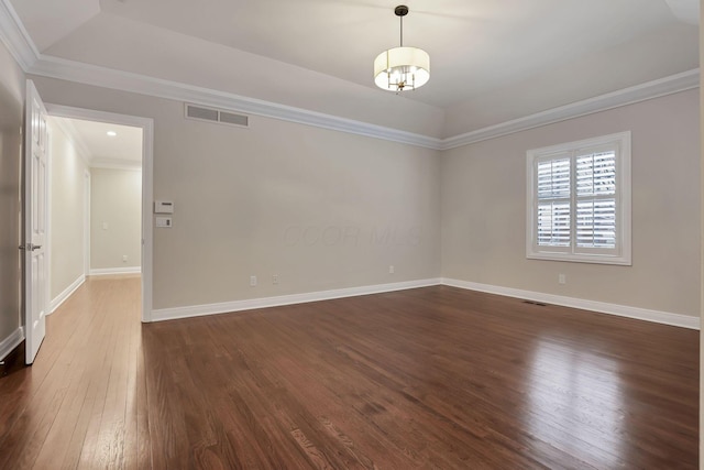 spare room featuring a chandelier, dark hardwood / wood-style flooring, ornamental molding, and a tray ceiling