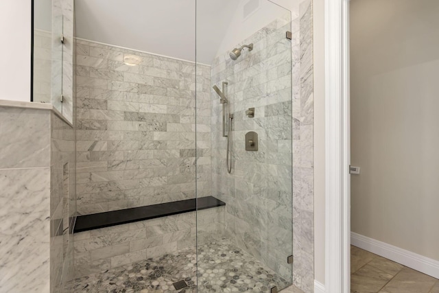 bathroom with a tile shower and lofted ceiling