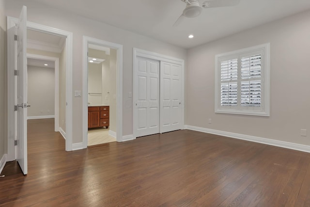 unfurnished bedroom featuring ceiling fan, dark hardwood / wood-style floors, ensuite bath, and a closet