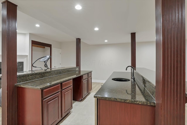 kitchen featuring dark stone countertops, kitchen peninsula, and sink