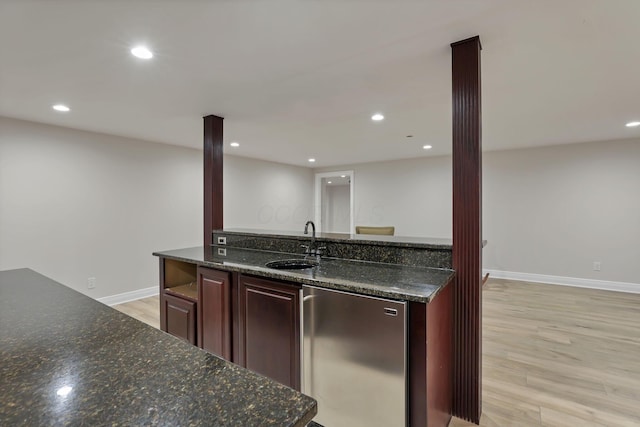 kitchen with sink, light hardwood / wood-style flooring, decorative columns, dark stone countertops, and fridge