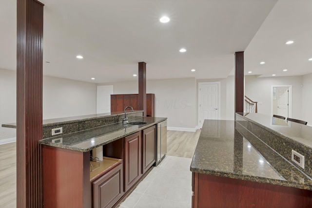 kitchen with a spacious island, dark stone counters, and sink