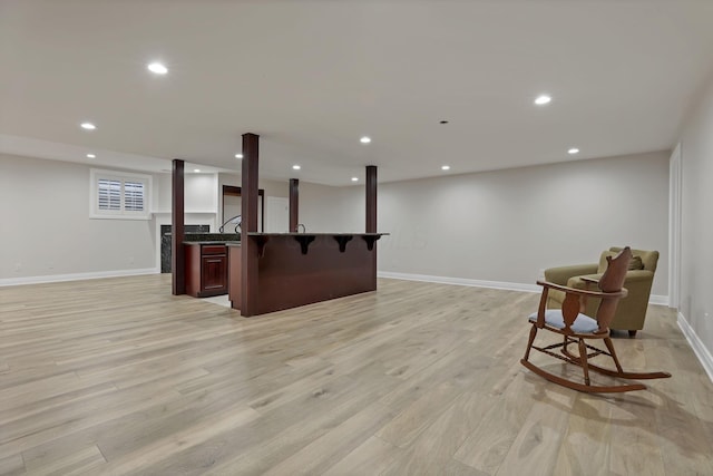 interior space with light wood-type flooring, a breakfast bar area, and an island with sink