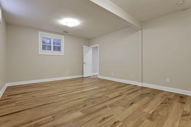 unfurnished room with beamed ceiling and light hardwood / wood-style flooring