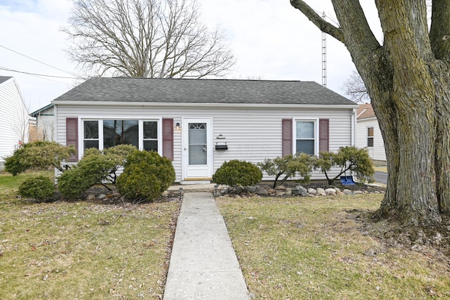 view of front of house featuring roof with shingles and a front yard